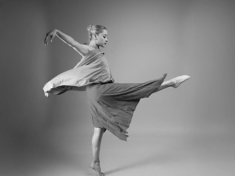 Person performing a fluid stretching movement in a minimalist studio.